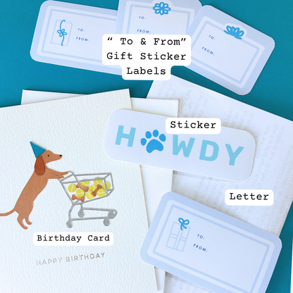 Birthday card with a dachshund pushing a shopping cart, a “Howdy” sticker, and stacked “To & From” gift sticker labels, with labels identifying the birthday card, sticker, and letter.