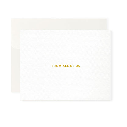 This image features a high-quality, professional greeting card and its matching envelope, set against a clean white background. The card itself is oriented horizontally, though it opens vertically. It is crafted from a heavy-weight, bright white paper with a sophisticated, rippled texture that gives it a premium, tactile appearance. Centered on the front of the card is the phrase "From All Of Us," printed in a clean, all-caps sans-serif font. The text is embossed in shiny gold-colored foil.