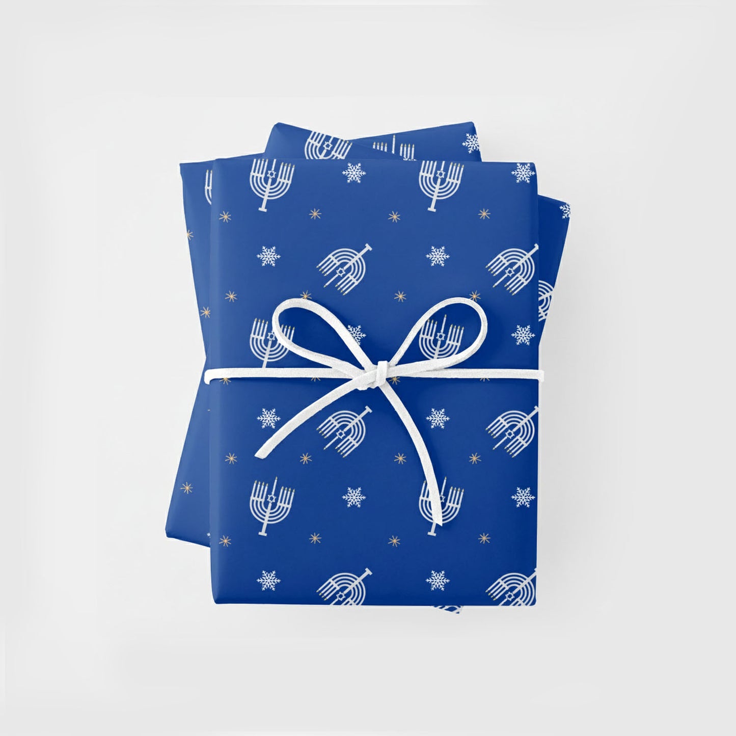 Blue gift wrap with Hannukah Menorah patterns and a white ribbon. The stack of three gifts  are centered on a light gray background.