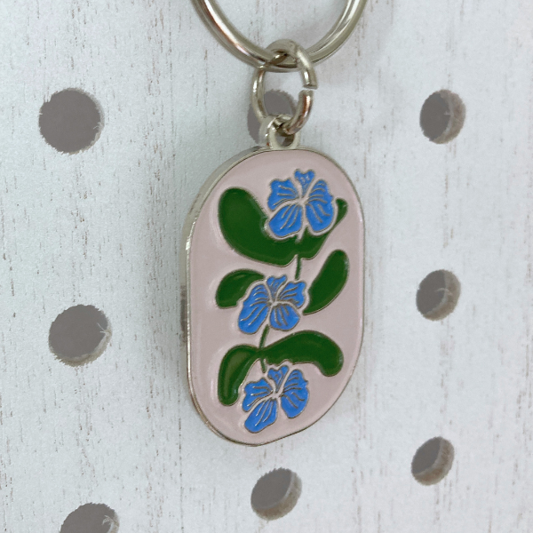 Side view of Flower Vine Soft Enamel Split Ring Keychain  hanging on a white peg board.