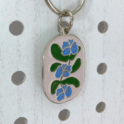 Side view of Flower Vine Soft Enamel Split Ring Keychain  hanging on a white peg board.