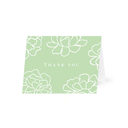 A light green horizontal folded card standing up with white line-art peony flowers and the text "Thank you" in a central uppercase serif font. The card is centered on a white background.