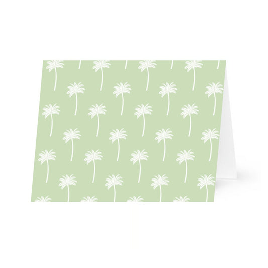 A horizontal greeting card featuring a palm tree pattern on a green background. The card is shown slightly propped open against a plain white background.