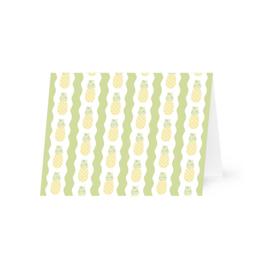 A single folded greeting card featuring a pattern of vertical rows of stylized pineapples. The pineapples have a yellow crisscross diamond pattern with green leafy tops, set against alternating white and green wavy vertical stripes. The patterned horizontal card is standing up slightly open and is centered on a white background.