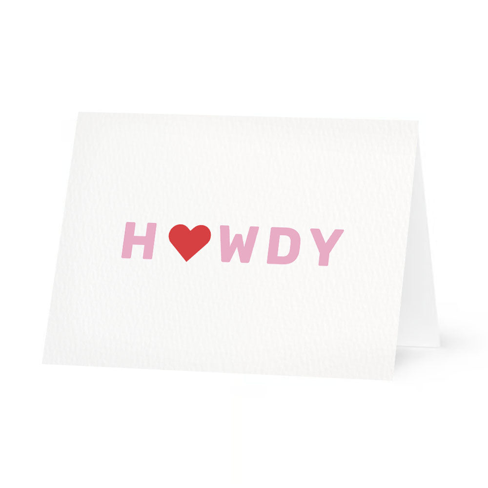 White horizontally folded greeting card with 'howdy"' text and a red heart replacing the o in "howdy. The card is centered on a white background.