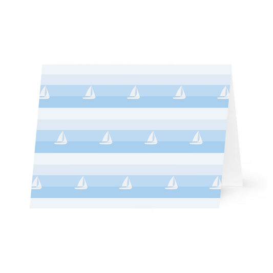 A single notecard featuring a pattern of horizontal blue stripes and white sailboats. The patterned horizontal card is standing propped open and it is centered on a white background.