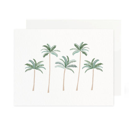 a horizontal folded greeting card made of textured white paper featuring five watercolor palm trees. the trees have tall, thin trunks and green fronds, arranged in a slightly staggered line. a white envelope is tucked behind the card.